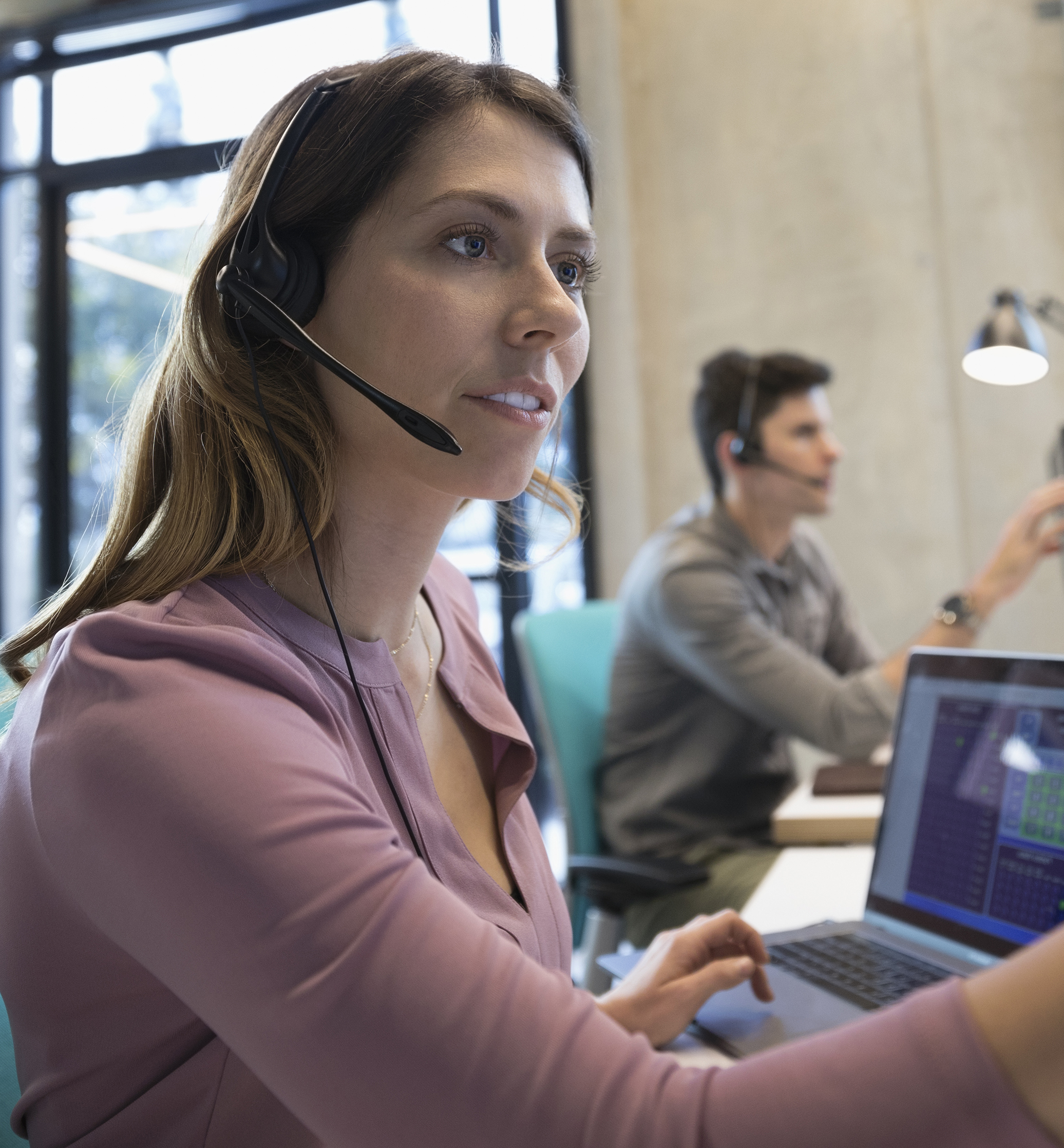 Technical support operator with headset working at laptop and computer